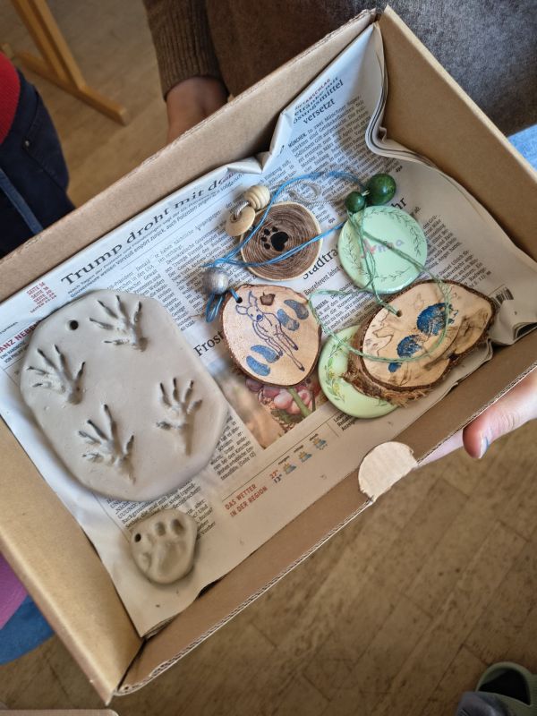 auf dem Bild hält ein Kind gebastelte Tierspuren in die Kamera
